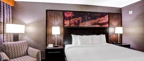 A hotel room with a large bed, two nightstands, a chair, and a wall-mounted TV.