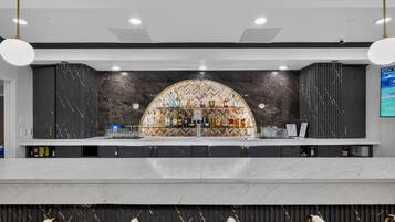 A bar area with a marble countertop, a selection of liquor bottles, and a herringbone patterned wall.