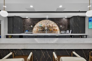 A bar area with a marble countertop, a selection of liquor bottles, and a herringbone patterned wall.