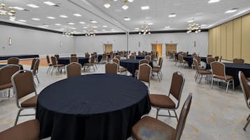 Een ruime congreszaal met meerdere tafels en stoelen, opgesteld in rijen.