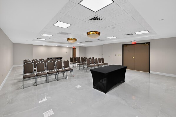 Un salón de conferencias con una mesa larga, filas de sillas y una puerta con la inscripción 'EXIT'.