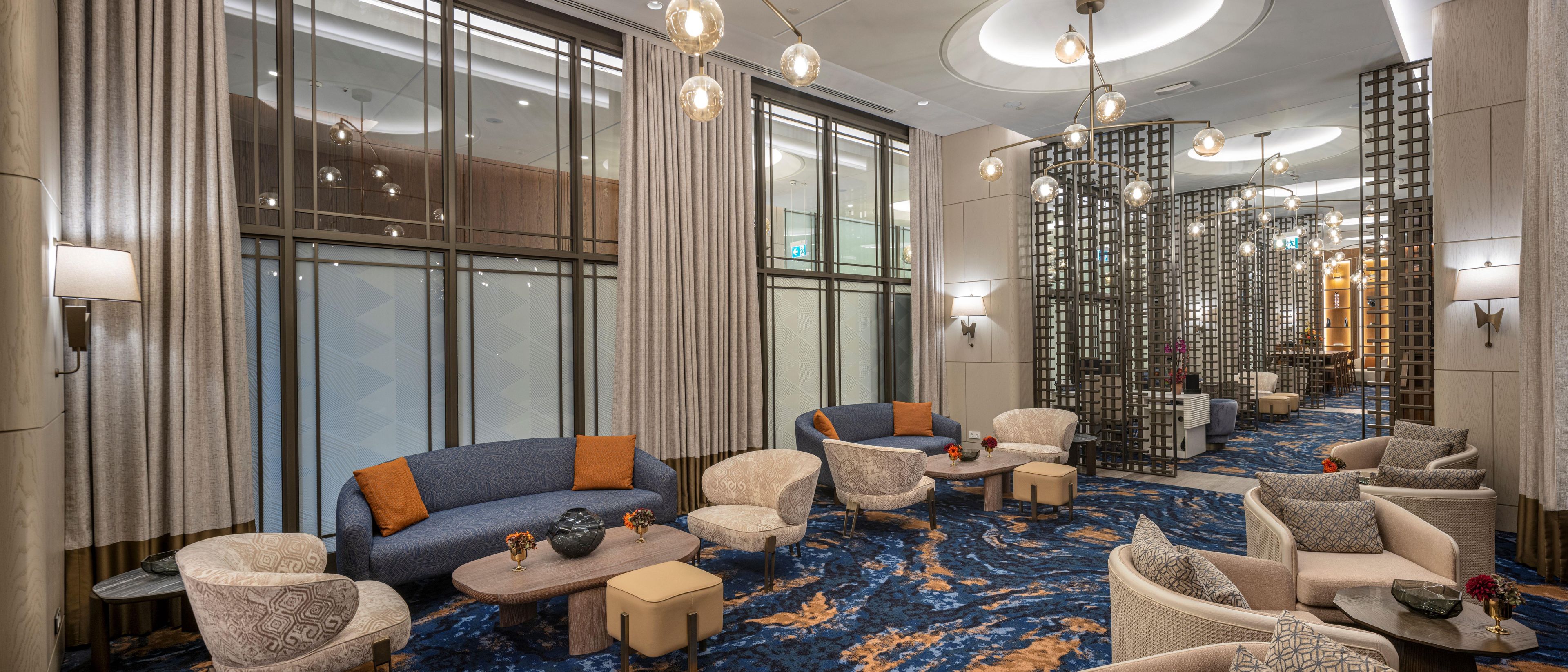 Een hotel lobby met zitgedeelte, een kamerbreed tapijt met dessin en een decoratieve wand.
