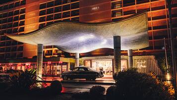 Un bâtiment moderne doté d’une structure de toit incurvée originale, une voiture garée devant et une enseigne indiquant qu’il s’agit d’un hôtel.