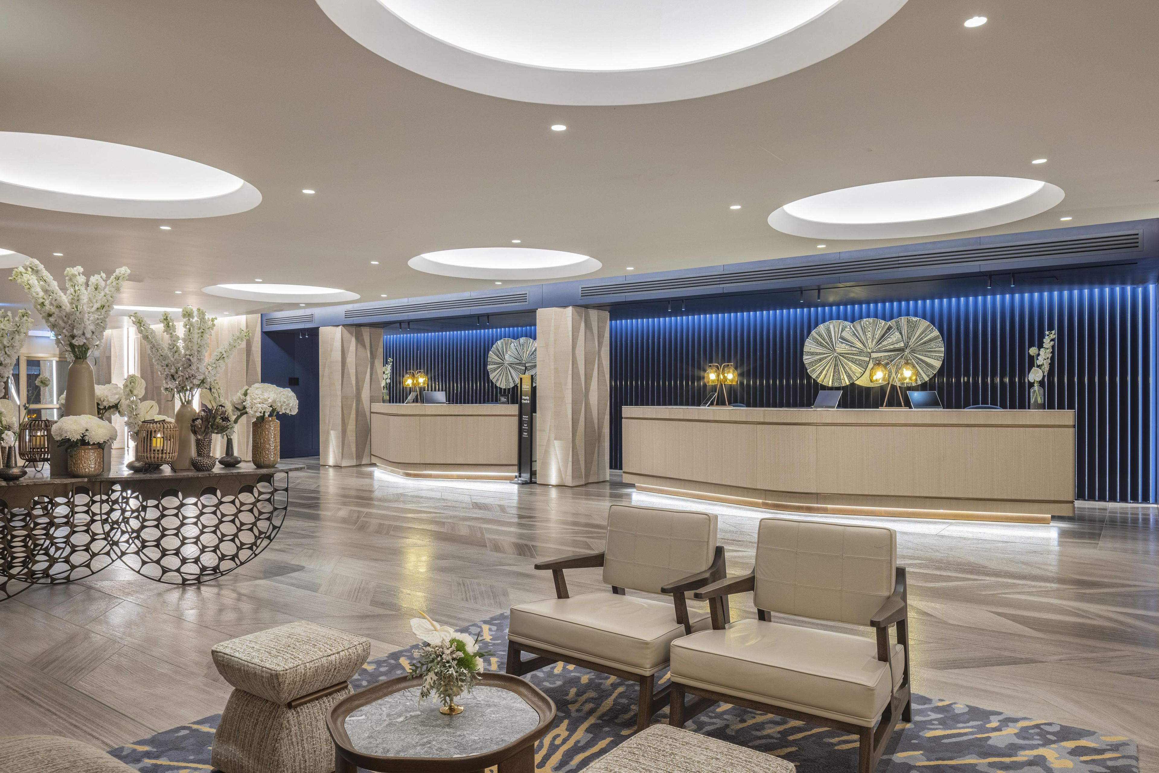 A modern hotel lobby with a reception desk, seating area, and decorative elements.