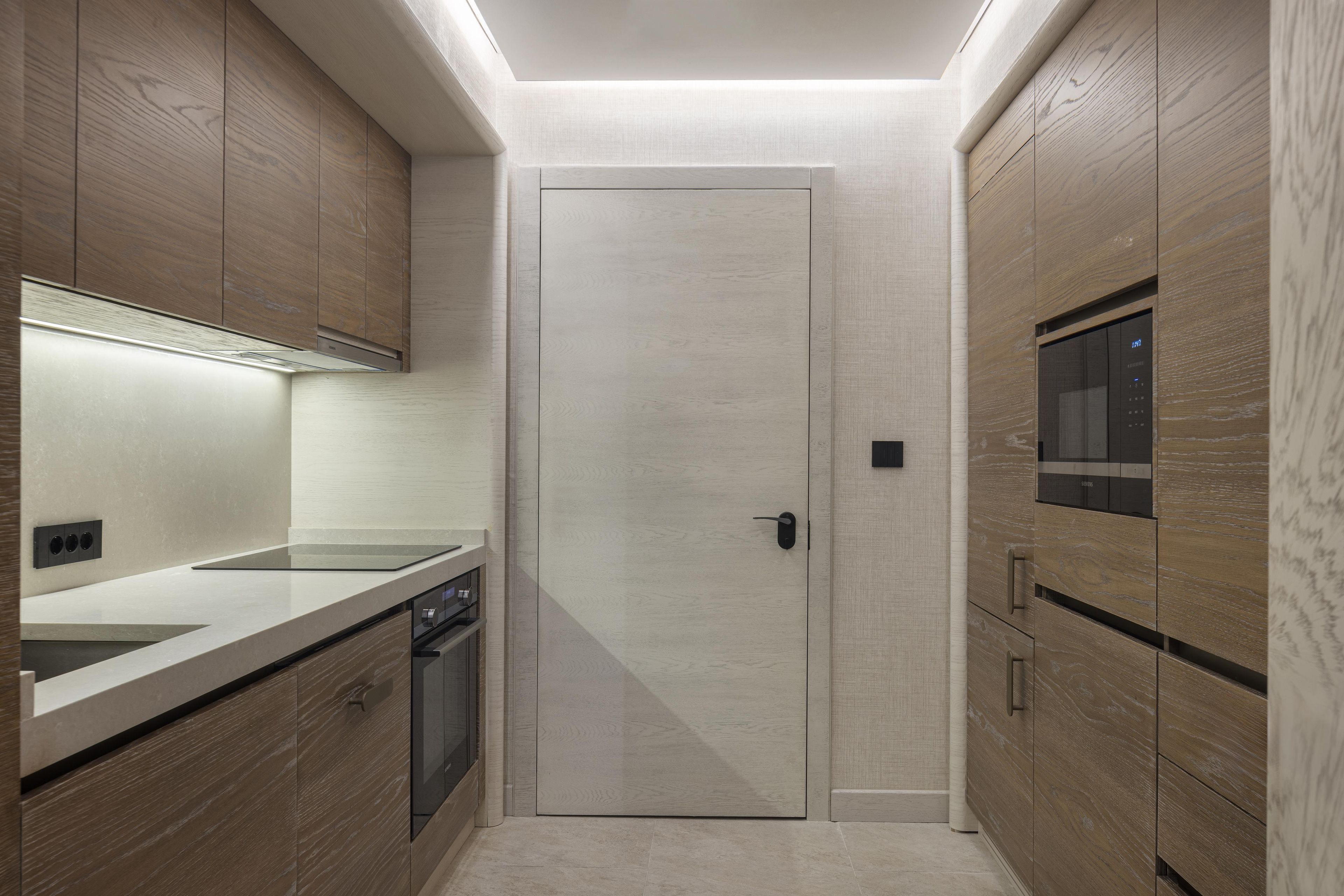 A modern kitchen with wooden cabinetry, a built-in oven, and a microwave.