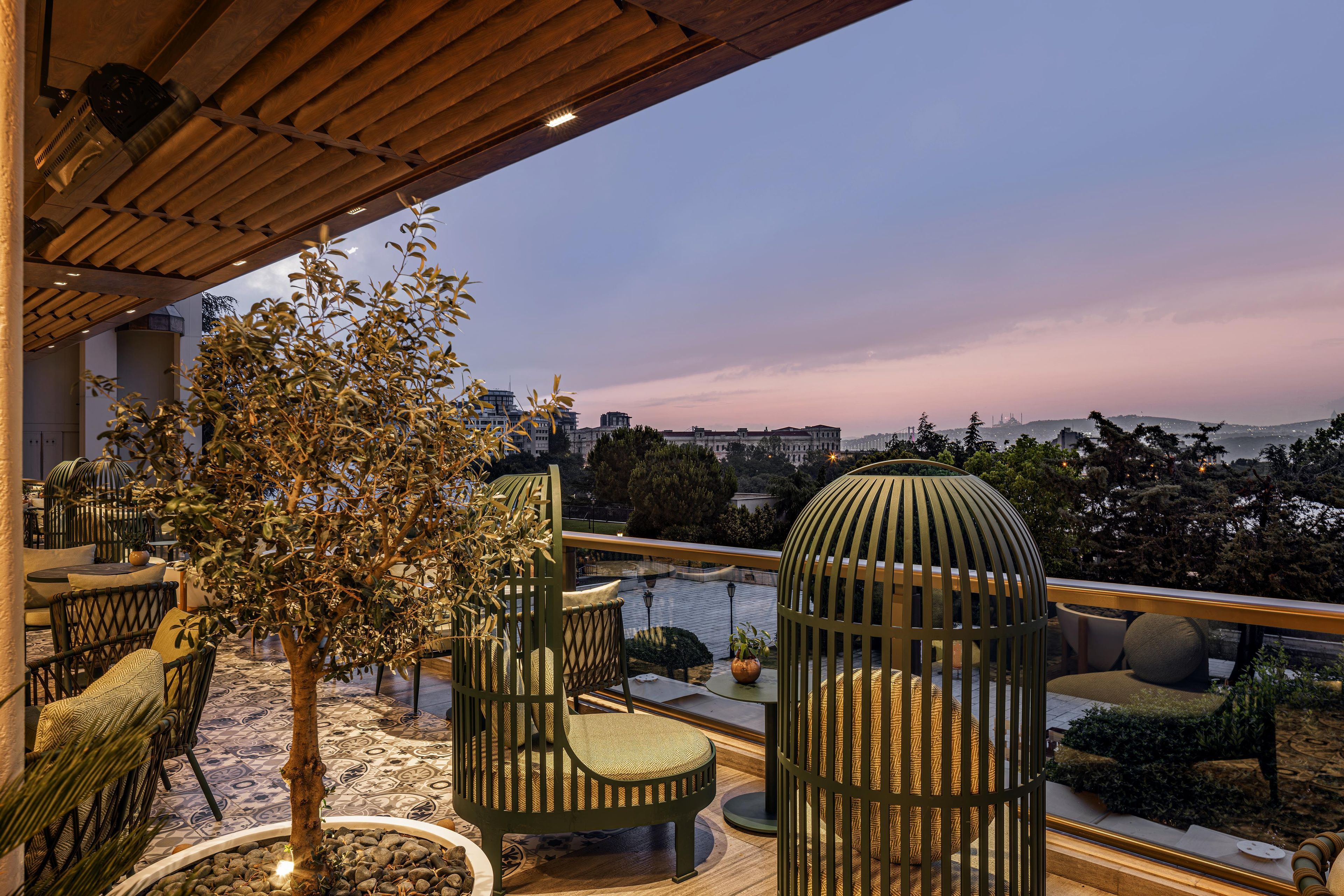 A terrace with outdoor seating, a tree, and a view of the cityscape.