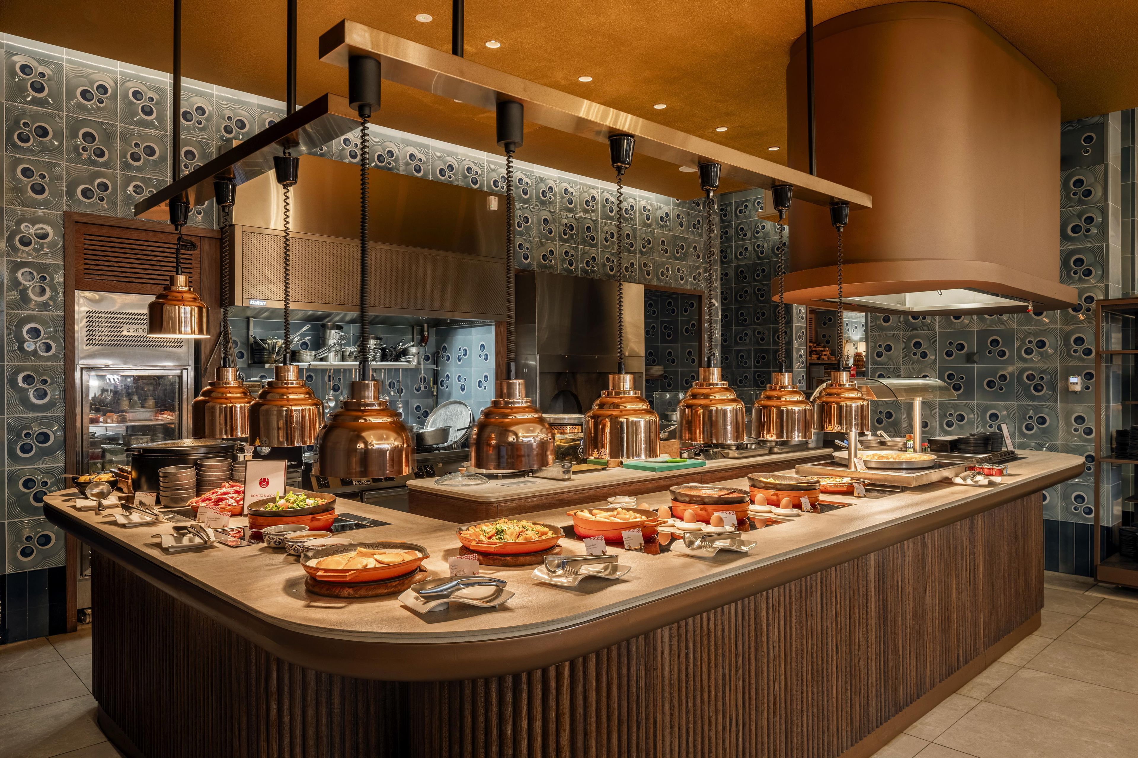 A modern kitchen with a central island, copper pots, and a variety of food items.