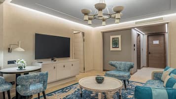 Un salón moderno con televisor de pantalla plana, una mesa de centro redonda y sillones tapizados azules a juego.