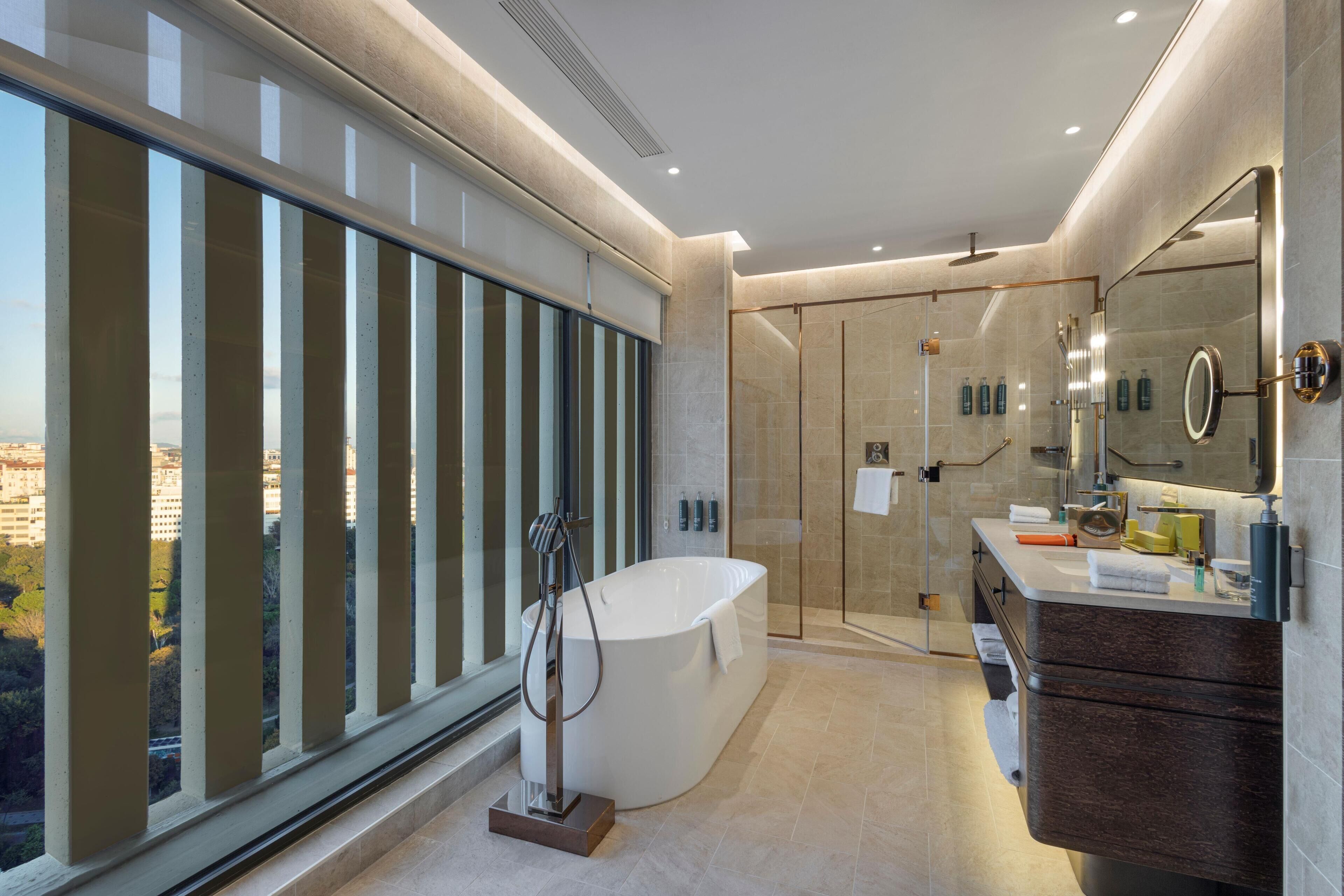Ein modernes Badezimmer mit einer großen Badewanne, einer begehbaren Dusche und einem Waschtisch mit Spiegel.