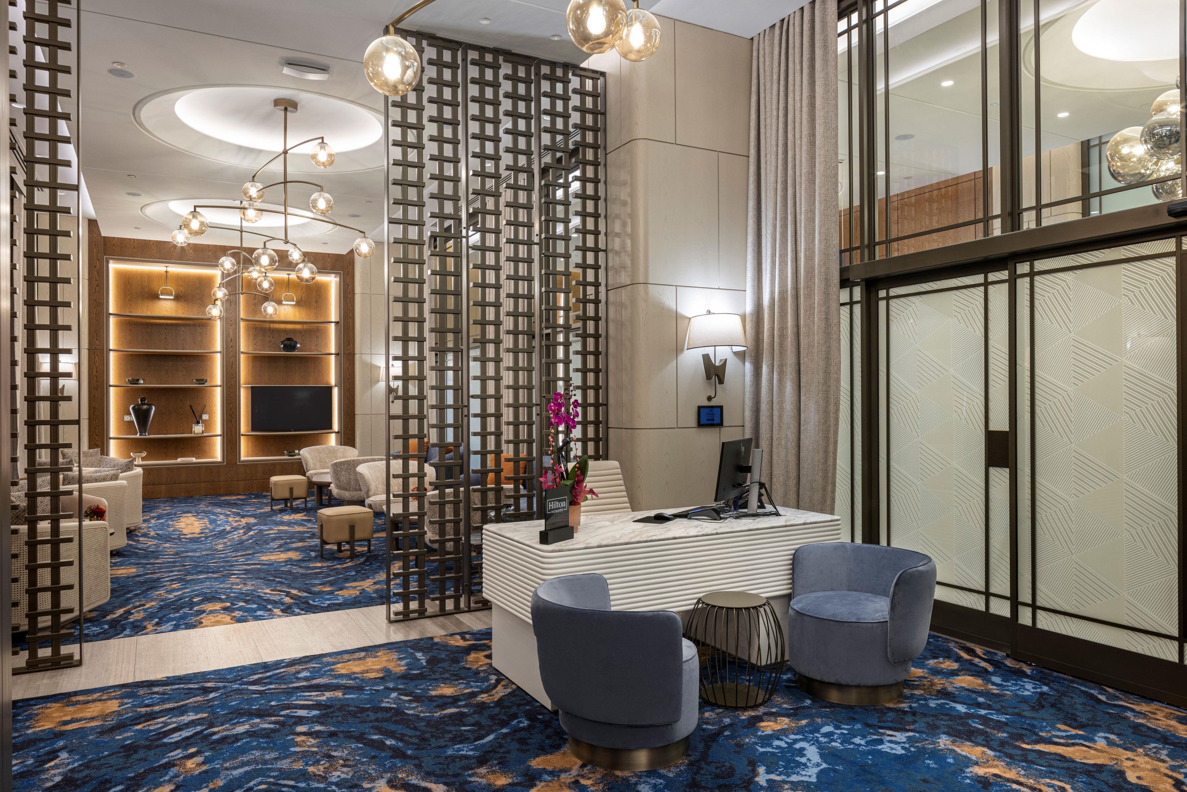 Eine moderne Hotelhalle mit Sitzgelegenheit, einer Rezeption und einem großen Fernseher.