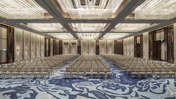 Una amplia sala de conferencias con filas de sillas y un suelo estampado.
