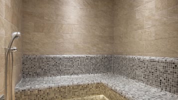 Un espace douche avec des murs carrelés et un banc en mosaïque de verre.