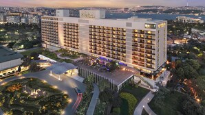 Un grand hôtel à plusieurs étages, doté d’une cour intérieure, entouré de verdure et offrant une vue sur le paysage urbain.