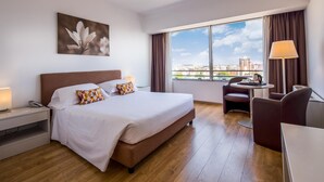 A hotel room with a large bed, a desk, a chair, a lamp, and a window with a city view. - Hotel Blaise & Francis (Milan)