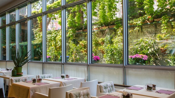 A restaurant with tables set for dining, large windows with a view of greenery and flowers. - Hotel Blaise & Francis (Milan)