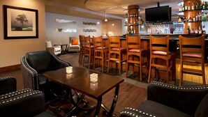 Un espace bar avec des chaises en bois, un comptoir et un téléviseur.