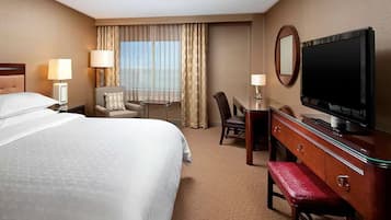 A hotel room with a bed, a desk, a television, and a chair.