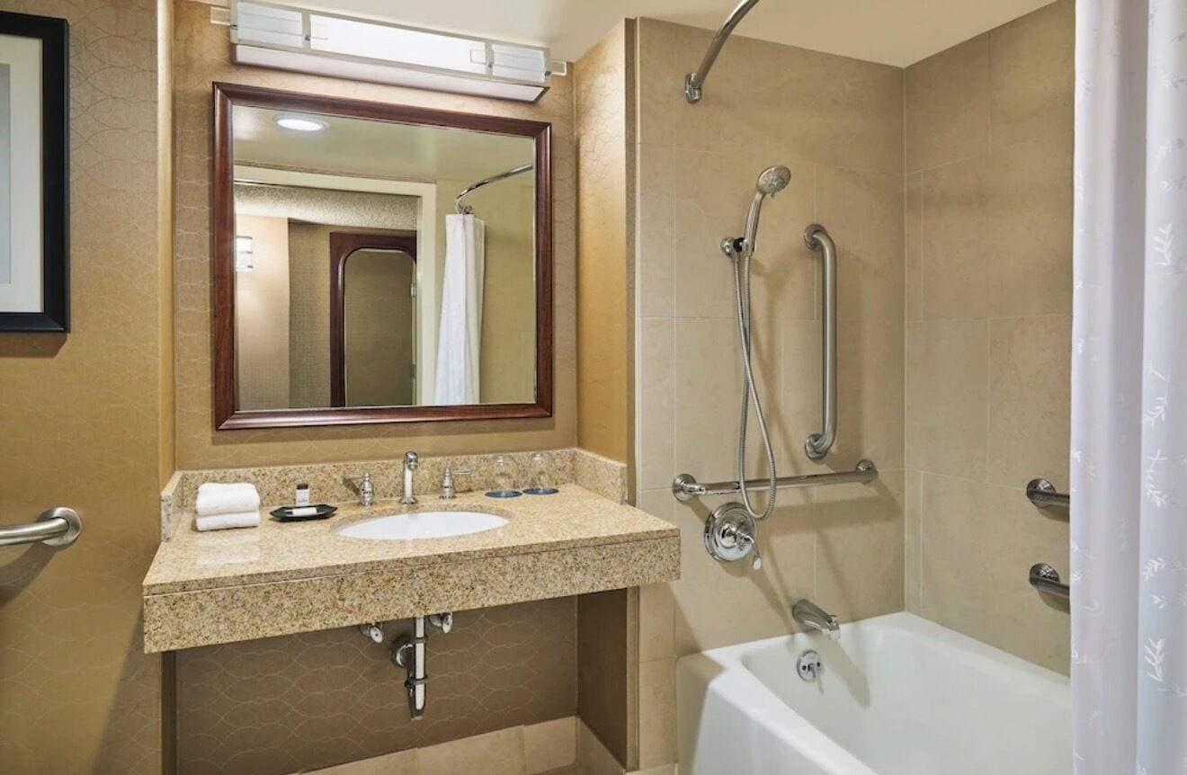 A bathroom with a sink, mirror, shower, and bathtub.