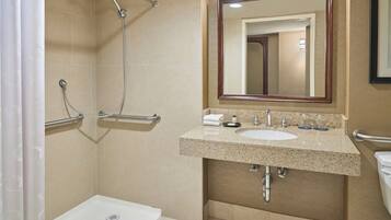 Une salle de bain équipée d’une douche, d’un lavabo, d’un miroir et de toilettes.