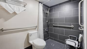 A modern bathroom with a toilet, a shower with a glass door, and a grab bar.