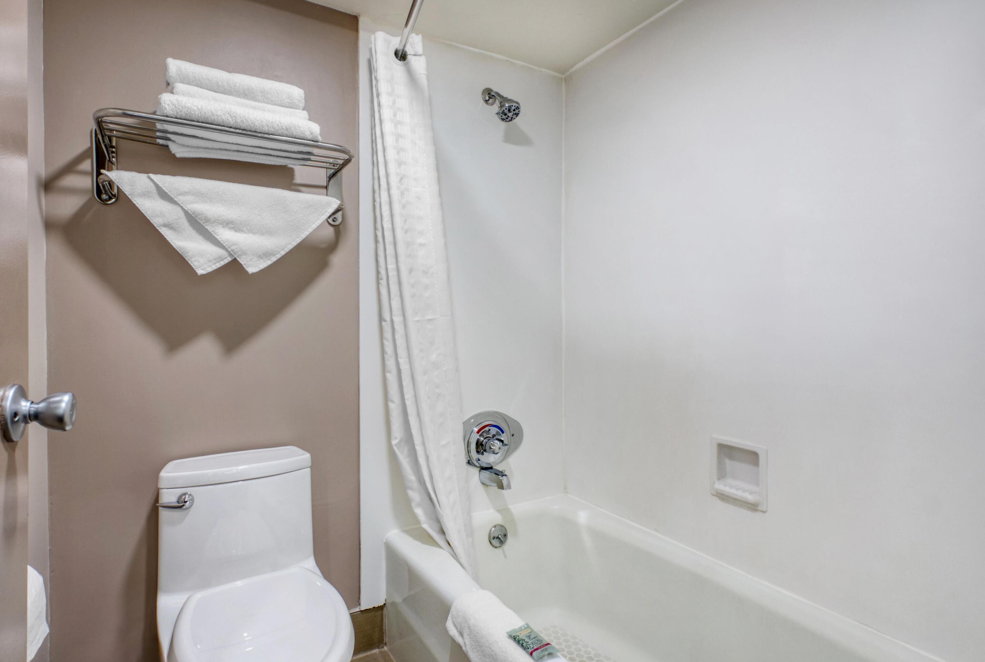 Un baño con inodoro, bañera y cortina de ducha.
