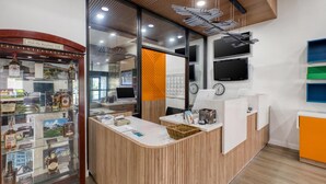 A reception desk with a wooden finish, a glass display case with liquor bottles, and a wall-mounted TV. - Best Western Shepherdsville-Louisville South Hotel (Shepherdsville)