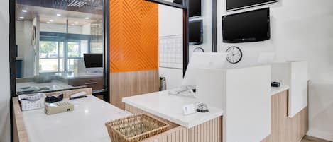 A reception desk with a computer, a clock, and a telephone.
