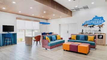 Una sala moderna con televisor, zona de estar y un mural en la pared.