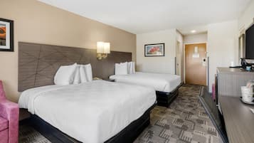 Habitación de hotel con dos camas, un escritorio, una silla y una puerta.