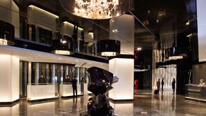 A modern lobby with a central sculpture, glass partitions, and a high ceiling with a chandelier. - The Mira Hong Kong Hotel (Kowloon)