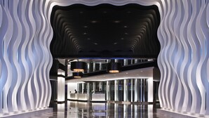 A modern lobby with a wavy ceiling design, a reception desk, and a glass partition. - The Mira Hong Kong Hotel (Kowloon)