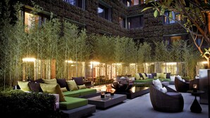 An outdoor seating area with sofas and chairs, a fire pit, and bamboo plants. - The Mira Hong Kong Hotel (Kowloon)