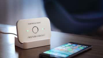 A Mira Hotel Collection charging station with a smartphone on a wooden surface.
