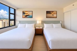 A hotel room with two beds, a nightstand with a lamp, and two paintings on the wall. - Aston at the Waikiki Banyan (Honolulu)