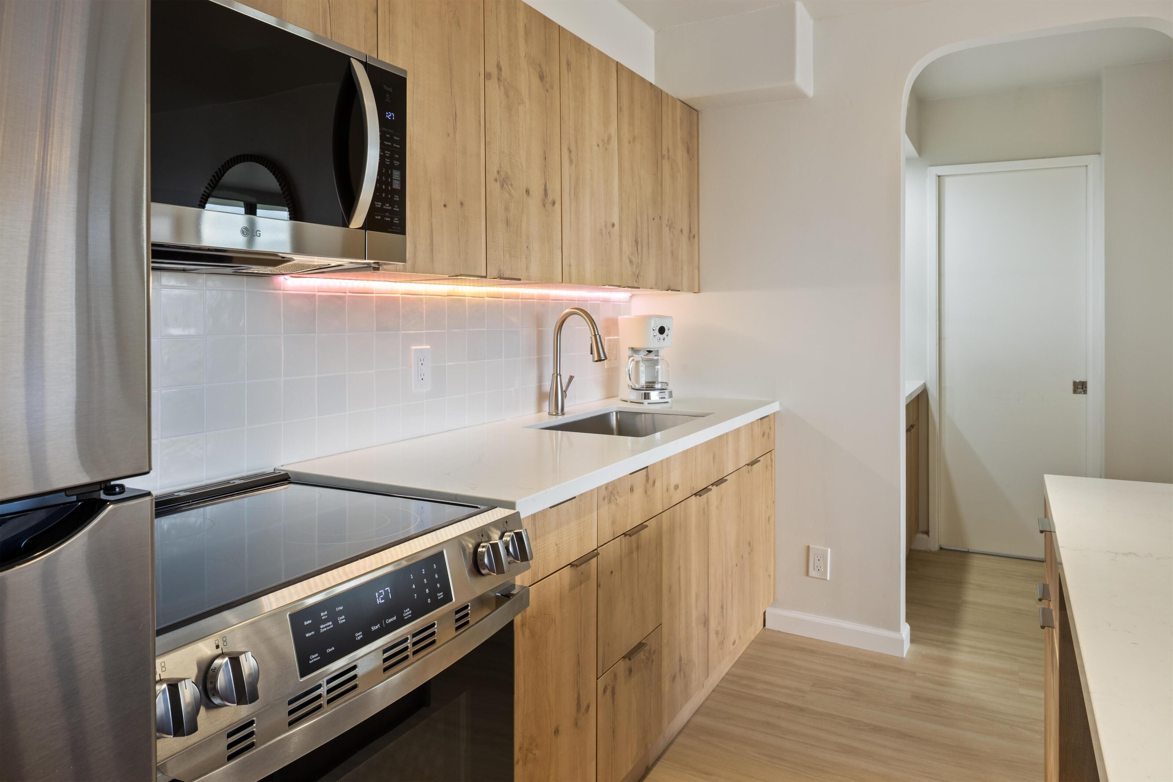 A modern kitchen with wooden cabinets, a stainless steel range, a microwave, and a coffee maker.