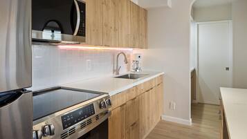 Een moderne keuken met houten kastjes, een roestvrijstalen fornuis, een magnetron en een koffiezetapparaat.