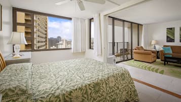 A hotel room with a bed, a sofa, a balcony, and a city view.
