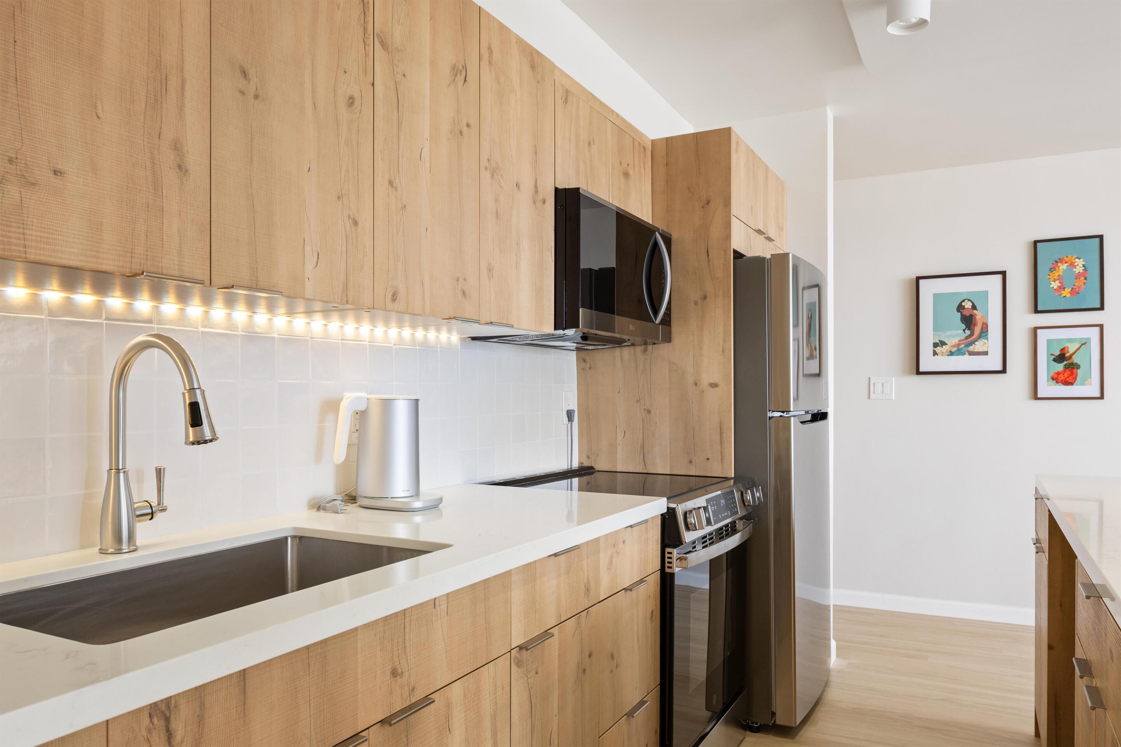 A modern kitchen with wooden cabinets, stainless steel appliances, and a white countertop.