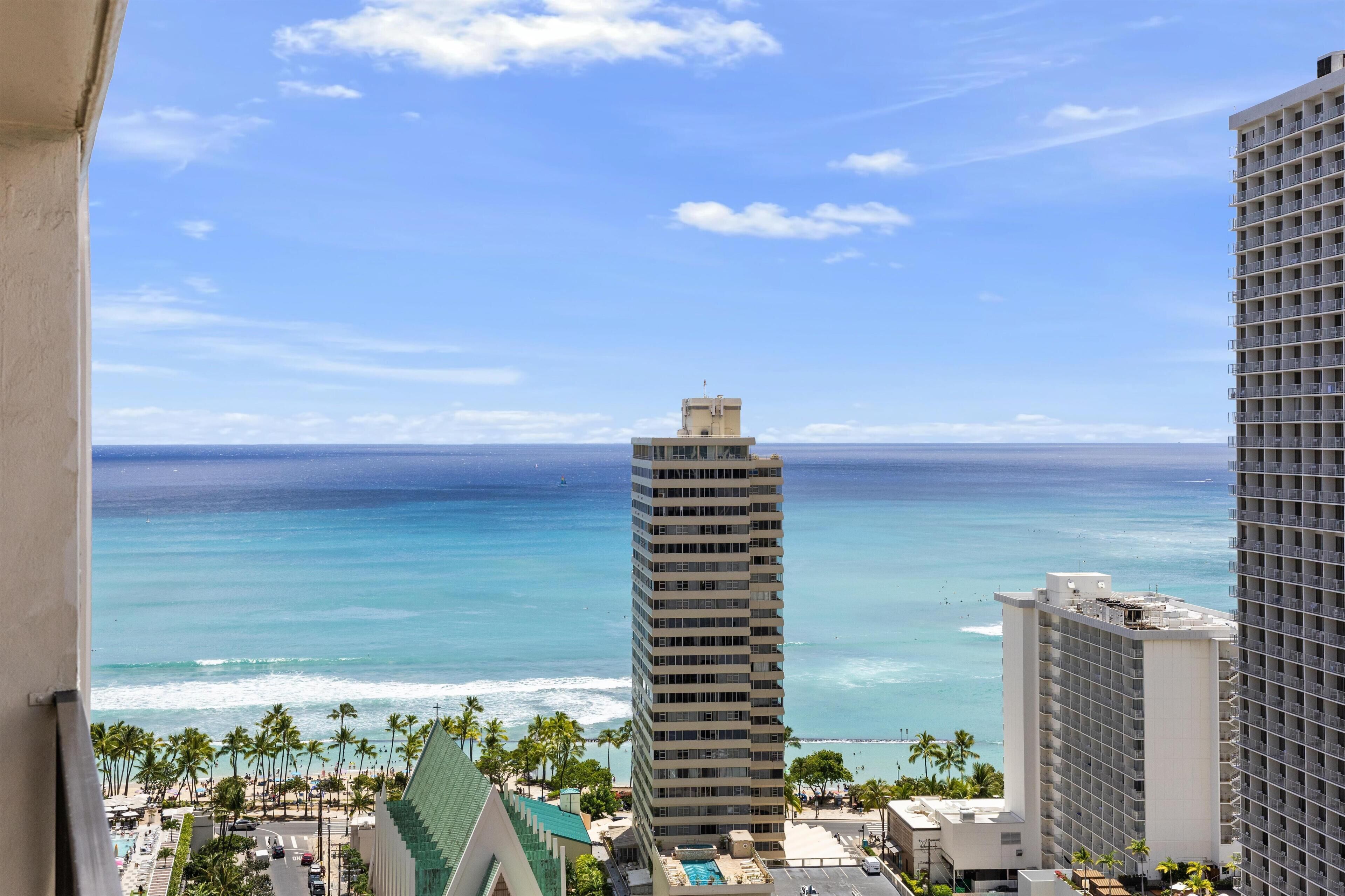 A high-rise hotel with a view of the ocean and palm trees.