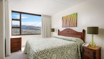 A hotel room with a bed, a nightstand, a lamp, a telephone, a window with a view of mountains, and a painting on the wall.