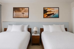 A hotel room with two beds, a nightstand with a lamp, and two framed pictures on the wall. - Aston at the Waikiki Banyan (Honolulu)