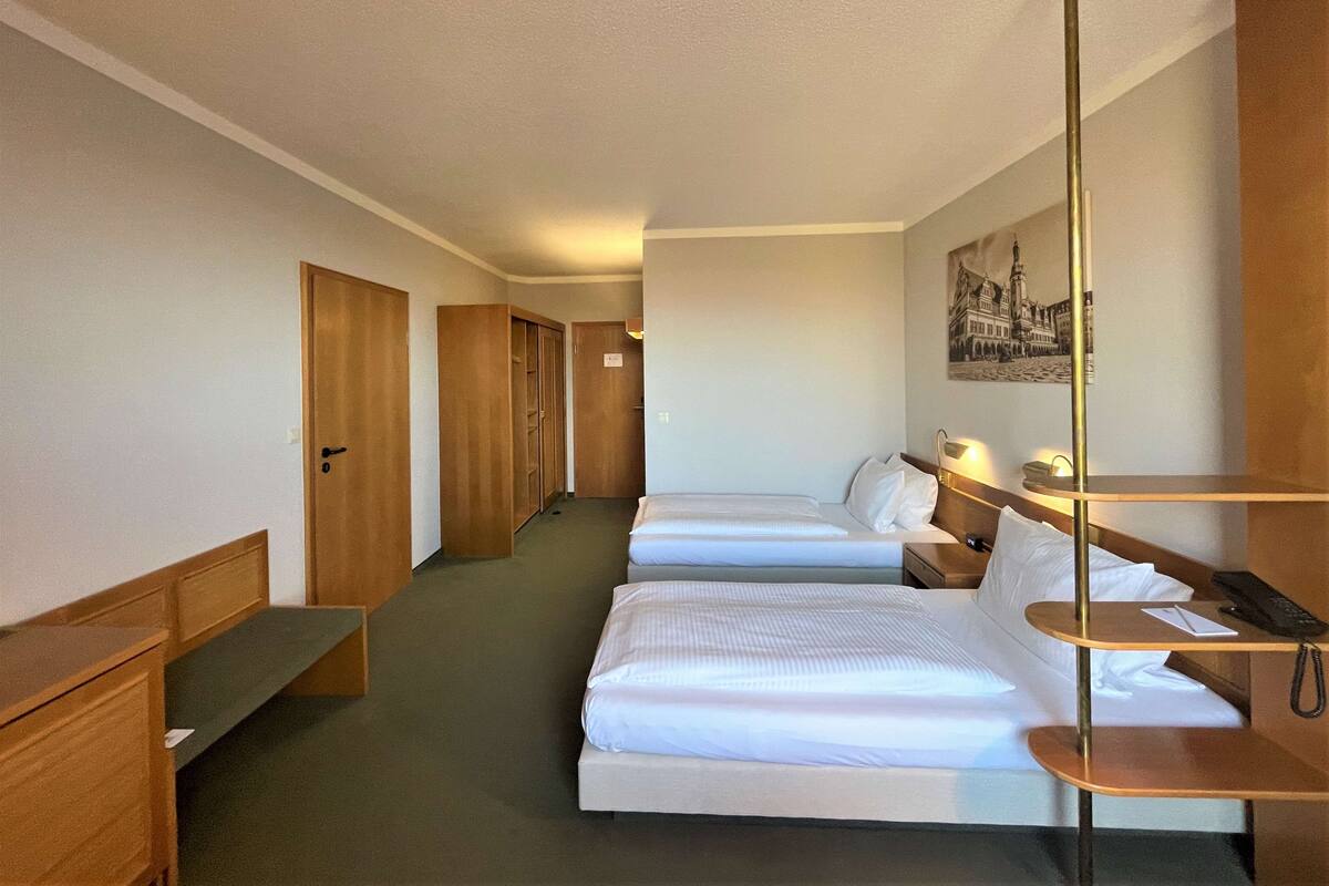 Habitación de hotel con dos camas, muebles de madera, un escritorio y una lámpara.