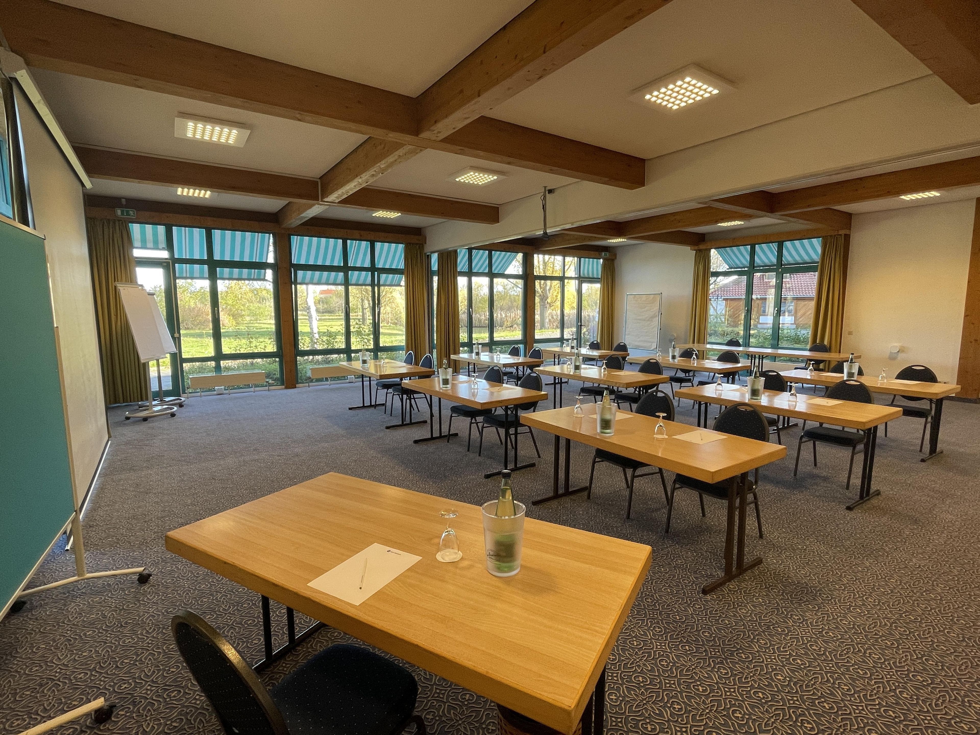A conference room with multiple tables and chairs, large windows, and a whiteboard.