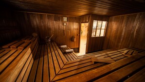 A sauna room with wooden benches and a wooden door leading to another room.