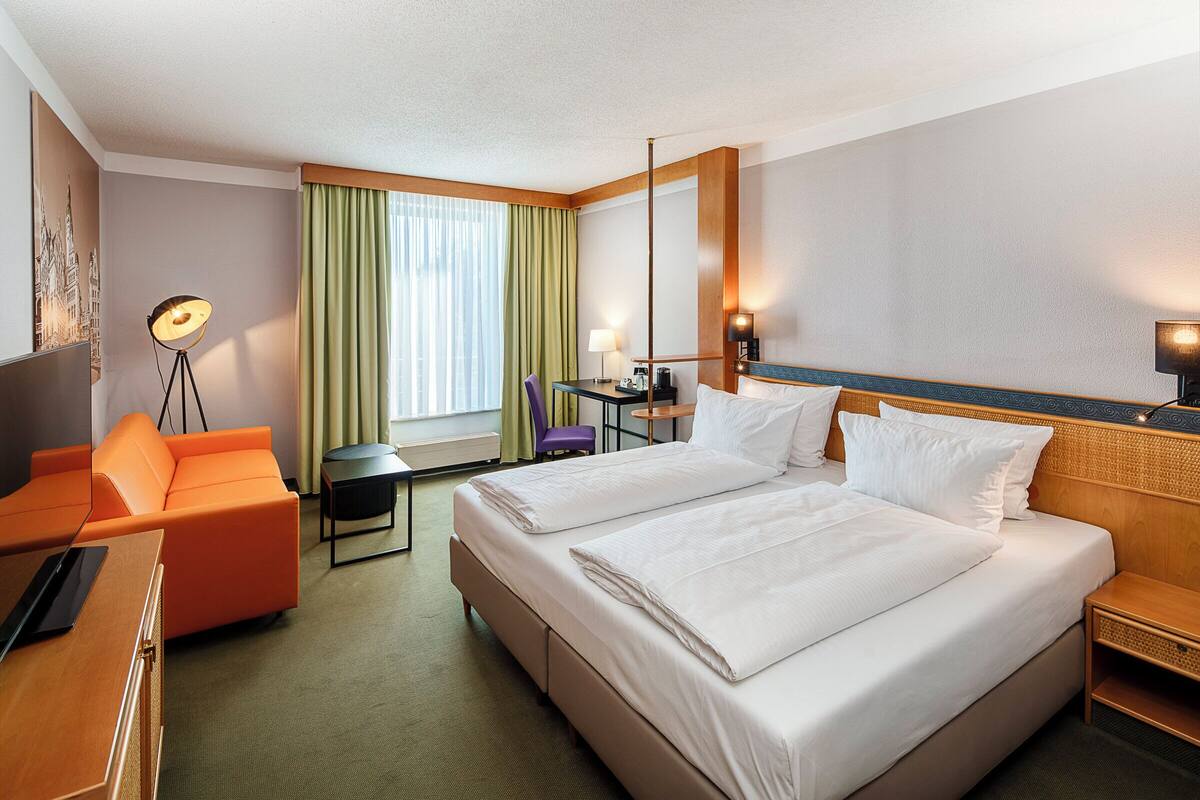 Una habitación de hotel con cama, escritorio, silla y sofá.