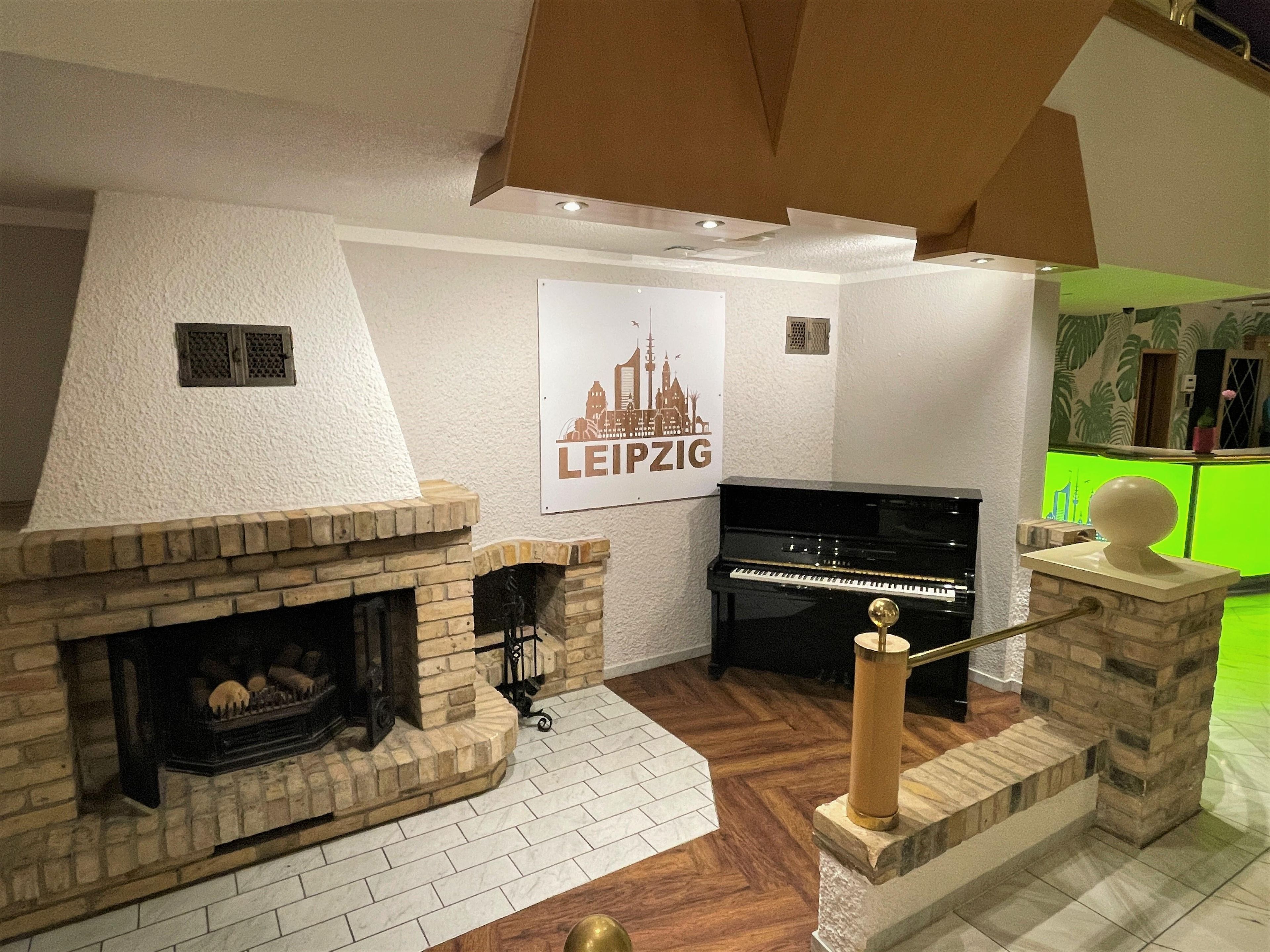 Un soggiorno con camino, un pianoforte e un poster di Lipsia.
