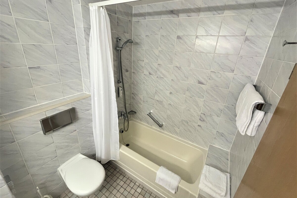 A bathroom with a bathtub, toilet, and shower area.