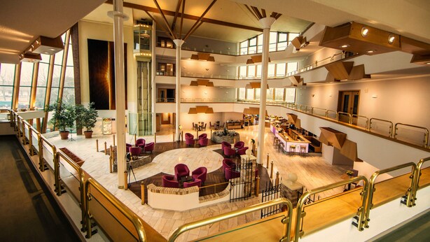 A spacious hotel lobby with a central seating area, multiple floors, and a modern design.