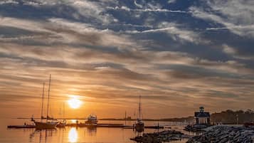 Un puerto tranquilo con barcos y un faro al atardecer.