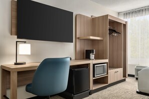 A hotel room with a desk, a chair, a flat-screen TV, a coffee maker, a mini-fridge, and a wardrobe. - Hyatt Select Williamsburg (Williamsburg)